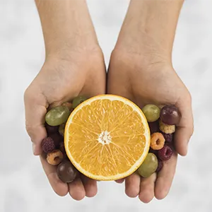 overhead view person s hand holding halved orange with grapes raspberry